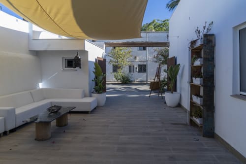 Terraza contemporánea de Cal Xot BnB en Poble Nou del Delta con asientos blancos, vela de sombra y plantas verdes