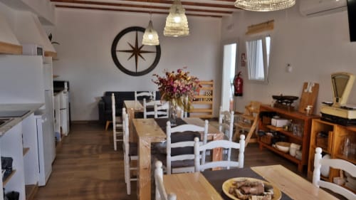 Zona de comedor de Cal Xot BnB en Poble Nou del Delta con mesas de madera, sillas blancas y decoración rústica
