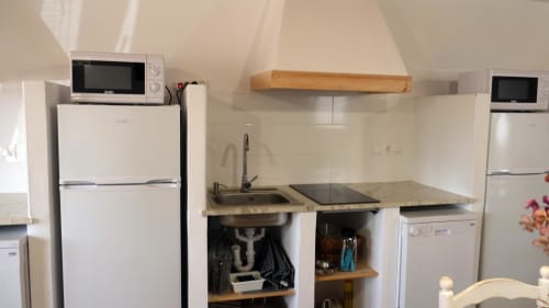 Pequeña kitchenette en Cal Xot BnB con microondas, frigorífico, fregadero y estanterías de madera en Poble Nou del Delta
