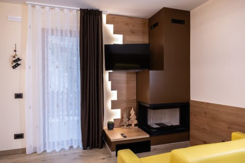 Camera da letto moderna presso Enro Mountain Vacation Home a Roccaraso con camino, TV a parete e mobili con accenti gialli