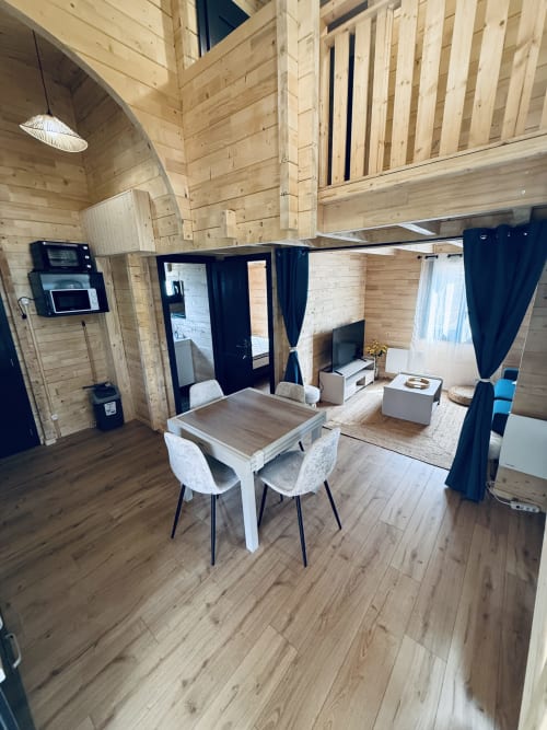 Intérieur du Lodge Shiloh avec poutres en bois, table à manger, cuisine et séparateurs en rideaux noirs