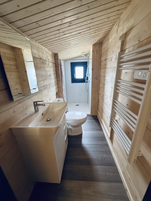 Salle de bain moderne du Lodge Shiloh aux Cabanes et lodges du Belvédère, Serrières-sur-Ain, avec murs en bois, lavabo, toilettes et