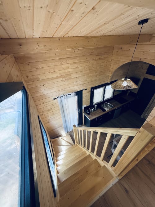 Intérieur du Lodge Shiloh aux Cabanes et lodges du Belvédère avec mezzanine en bois, bureau, escalier et luminaire