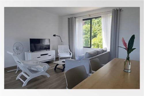 Modern apartment living area at Joubarbe Résidence, Moka with dining table, sofa, TV, mountain views and contemporary