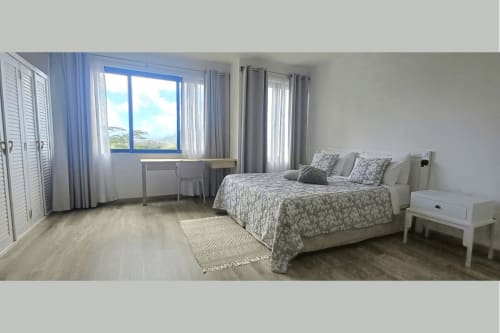 Spacious bedroom at Joubarbe Résidence in Moka with mountain views, modern furnishings, and natural light from large windows