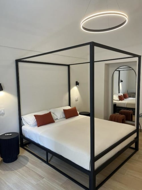 Elegante letto a baldacchino moderno presso la boutique hotel Marelia Suites a Vasto, Italia, con biancheria bianca e cuscini color ruggine