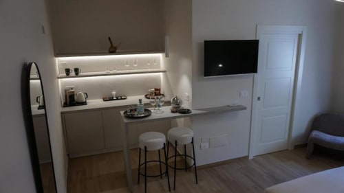 Angolo cottura moderno presso Marelia Suites a Vasto con bancone bar, scaffali LED e TV a parete
