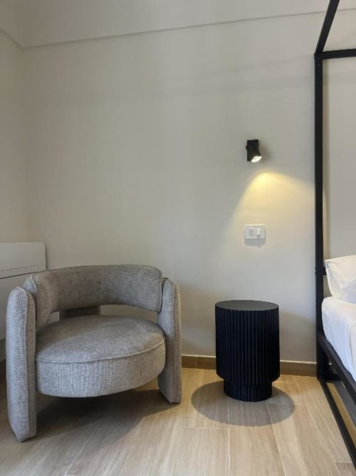 Camera moderna presso Marelia Suites Vasto con poltrona grigia, tavolino nero e illuminazione direzionale a parete