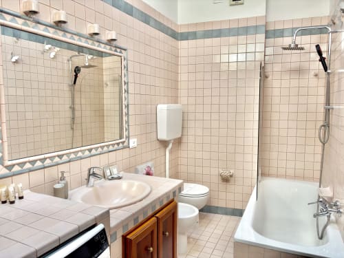 Bagno moderno nell'appartamento Manu Maison a Parma con lavabo, specchio, wc, vasca e doccia walk-in