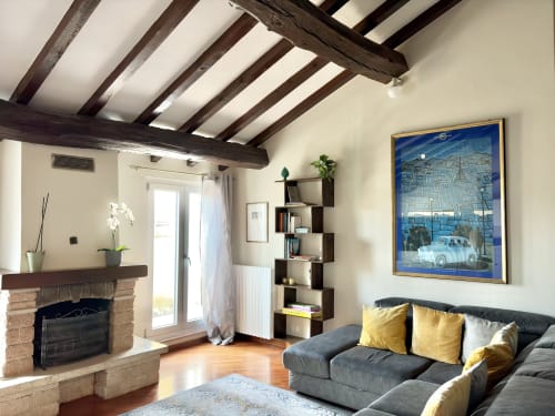 Moderno salotto a Parma con travi in legno a vista, camino, divano scuro con cuscini gialli e scaffalature