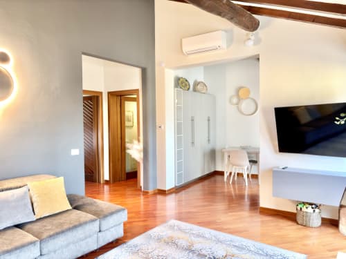 Soggiorno moderno a Parma con divano grigio, TV, pavimenti in legno, armadio bianco e piatti decorativi