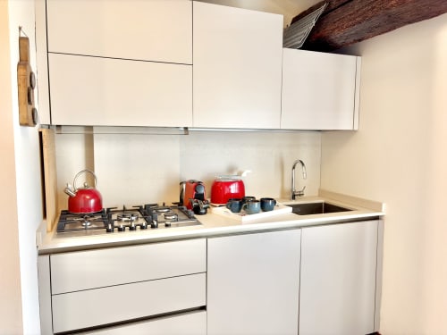 Cucina moderna dell'appartamento Manu Maison a Parma con mobili bianchi, fornello a gas, bollitore rosso e elettrodomestici da bancone