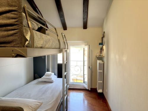 Camera con letto a castello a Parma con vista sulla città, biancheria bianca, pavimento in legno e balcone