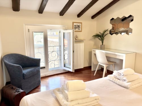 Elegante appartamento con vista Torre Civica a Parma: camera, scrivania, porte balcone, travi in legno scuro e arredamento moderno
