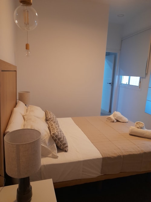 Modern bedroom at G&H Apartments in Jerez de la Frontera with queen bed, wooden furnishings, and contemporary pendant light
