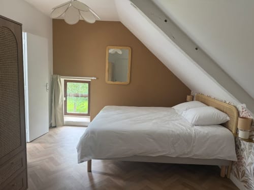 Chambre mansardée lumineuse au Clos de l'Arguenon avec lit queen-size, murs beige et vue sur le jardin