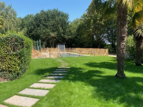 Pelouse verdoyante avec allée pavée menant au jardin clôturé du gîte Le Clos de l'Arguenon, Val-d'Arguenon