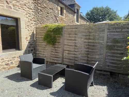 Coin terrasse extérieur du gîte Le Clos de l'Arguenon avec mobilier en rotin et clôture en bois à Val-d'Arguenon