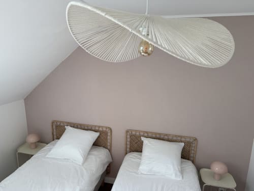 Chambre double avec têtes de lit en rotin tressé, linge blanc et luminaire suspendu moderne au gîte Le Clos de l'Arguenon