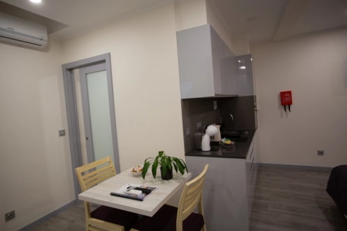 Modern apartment kitchen and dining area at Tropical Solutions in Funchal with white cabinetry and yellow chairs