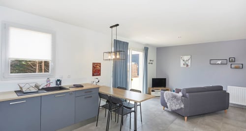 Toronto Apartment at Résidence des Sables in Mably: modern open-plan living with blue kitchen, dining area, grey sofa, and