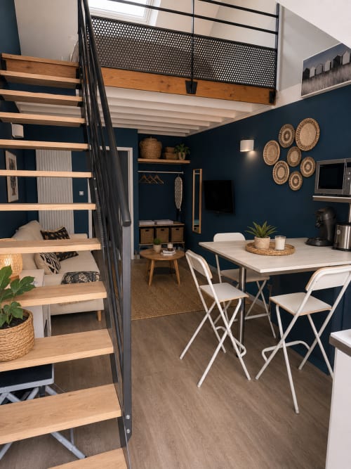 Appartement moderne à La Parenthèse Mancelle au Mans avec lit mezzanine, coin repas, kitchenette, murs bleu foncé et bois