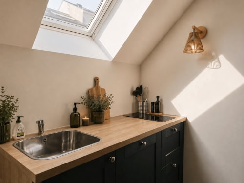 Kitchenette moderne de l'appartement L'Orée des Bois à La Parenthèse Mancelle avec comptoirs bois, armoires noires et inox