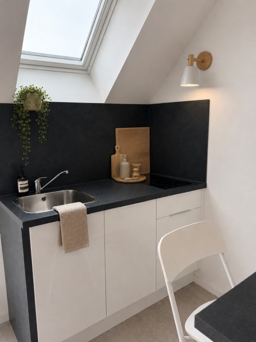 Salle de bain moderne au Parenthèse Mancelle au Mans : dosseret noir, meubles blancs, puits de lumière et détails en bois