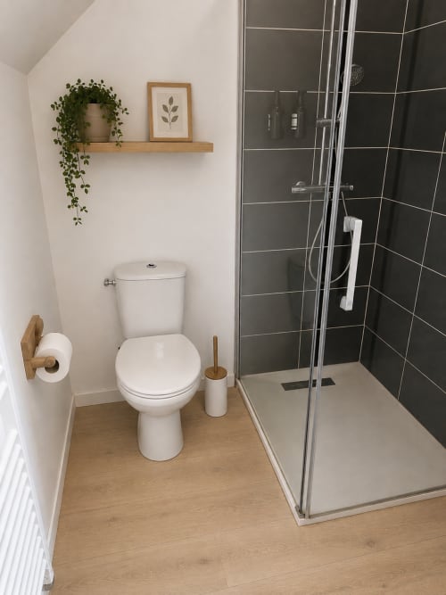 Salle de bain moderne de l'appartement Le Cocon végétal à La Parenthèse Mancelle au Mans, avec toilettes blanches et douche carrelée noire