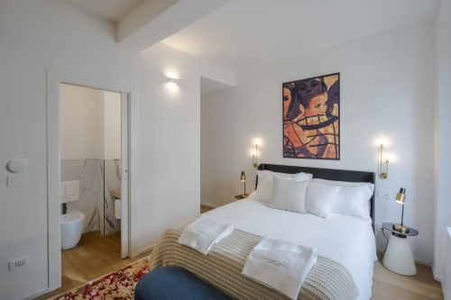 Camera moderna a Manu Maison a Parma con biancheria bianca, testata nera e bagno en-suite