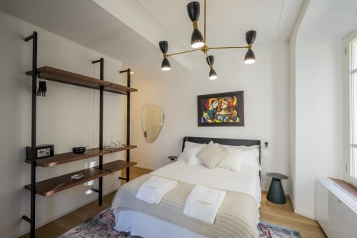 Camera moderna a Manu Maison a Parma con biancheria bianca, testata nera, scaffali in legno, lampade sospese e design contemporaneo