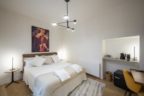 Camera moderna di Manu Maison a Parma con letto in legno, lampade sospese, zona studio e arredamento contemporaneo