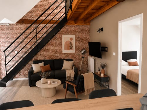 Suite loft contemporaine à La Parenthèse Mancelle avec escalier noir, murs en brique et mobilier design au Mans