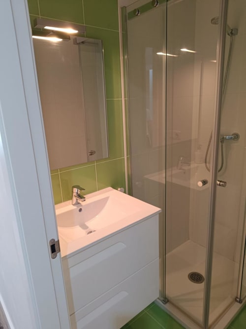 Modern bathroom with white sink vanity, green tile accents, and glass shower enclosure at Mediterranea Sunny Keys, Benicàssim