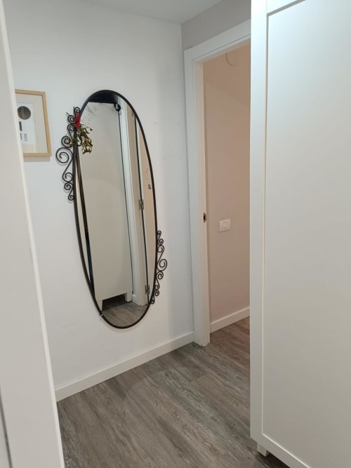 Modern hallway with decorative oval mirror and wooden flooring at Mediterranea Sunny Keys apartment in Benicàssim