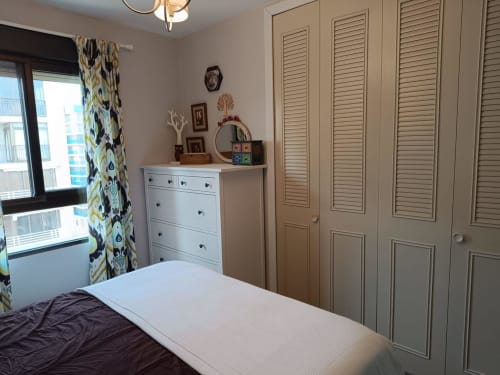 Modern bedroom in Riviera Sunny Flat, Benicàssim with white dresser, louvered wardrobe, patterned curtains and city views