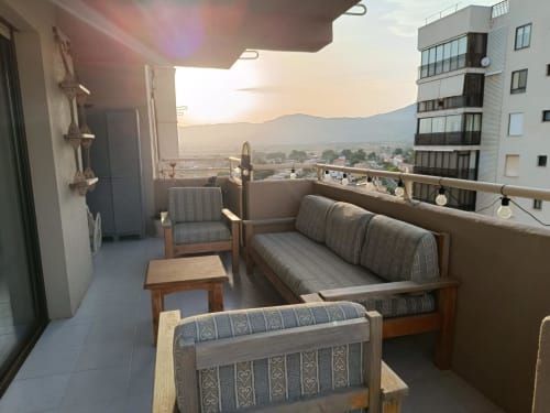 Riviera Sunny Flat terrace in Benicàssim with wooden furniture, sea views, and mountain backdrop at sunset