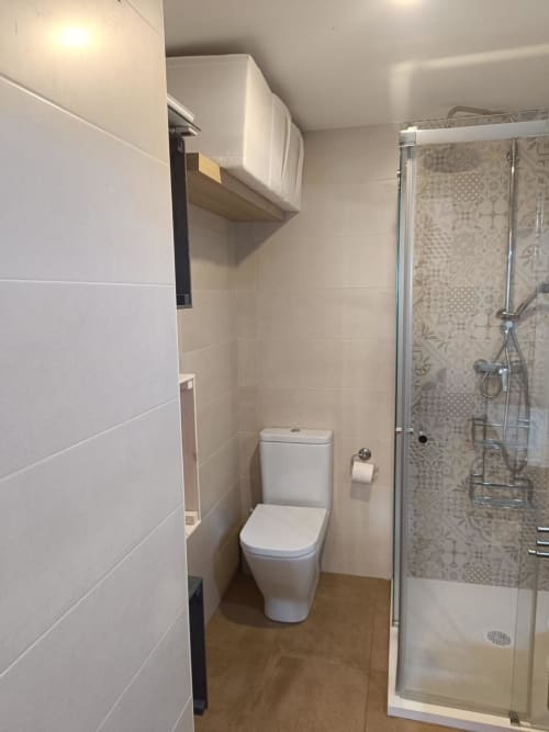 Modern bathroom with white toilet, glass shower enclosure, and patterned tiles at Mediterranea Sunny Keys apartment