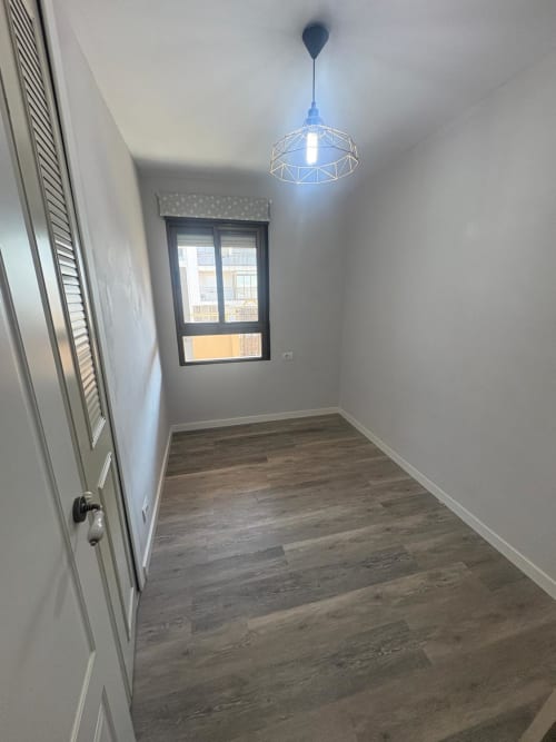 Modern apartment corridor with wooden flooring, geometric pendant light, and window with city views at Mediterranea Sunny