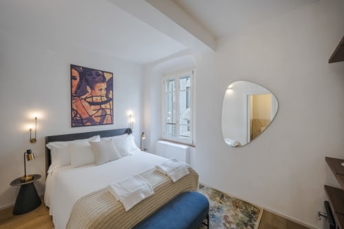 Camera da letto moderna a Manu Maison a Parma con biancheria bianca, arte astratta a parete, specchio rotondo e pavimento in legno