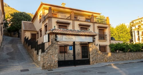 Albergue Hospedería Puerta a los Cahorros en Monachil con base de piedra, tejado de barro y postigos de madera