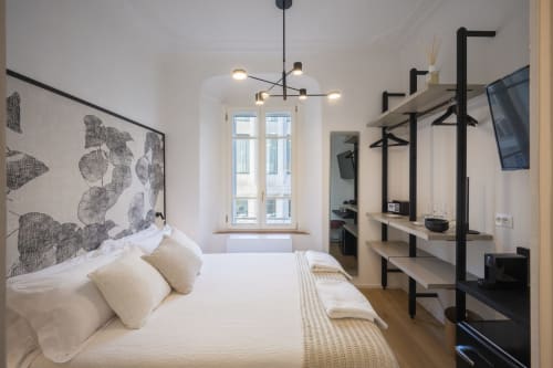 Camera da letto moderna dell'Hotel Parma con letto bianco, testata con arte botanica, luci a sospensione, mensole in legno e ampia finestra