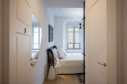 Camera luminosa di Manu Maison a Parma con letto, finestre e porte color crema con maniglie in ottone