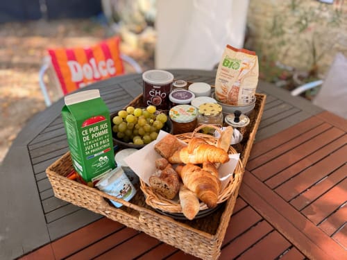 Panier petit-déjeuner au Domaine Valenquercy avec croissants, raisins, jus, céréales et tartinades sur table extérieure