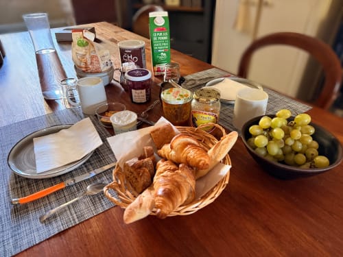 Petit-déjeuner français à la Domaine Valenquercy B&B : croissants, raisins, jus et pâtisseries sur table en bois