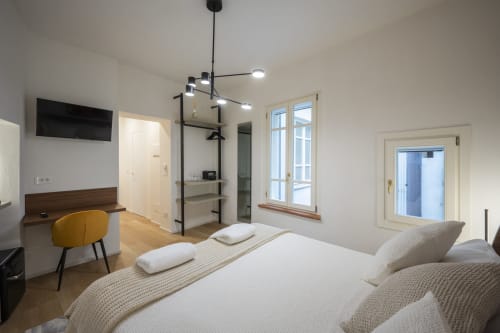 Camera moderna a Manu Maison a Parma con letto matrimoniale, scrivania, sedia gialla e accesso al balcone