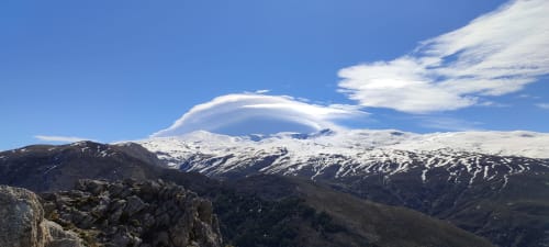 Montañas nevadas cerca de Monachil con nubes lenticulares sobre las cimas de Sierra Nevada