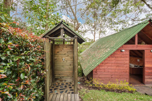 Cabaña de glamping de madera con techo verde en Sukha Glamping de Ríonegro, rodeada de exuberante vegetación y árboles