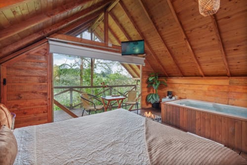 Habitación Sukha Glamping Arrayanes en Ríonegro: cama, vigas de madera, vista al jardín, jacuzzi y terraza con vistas al bosque