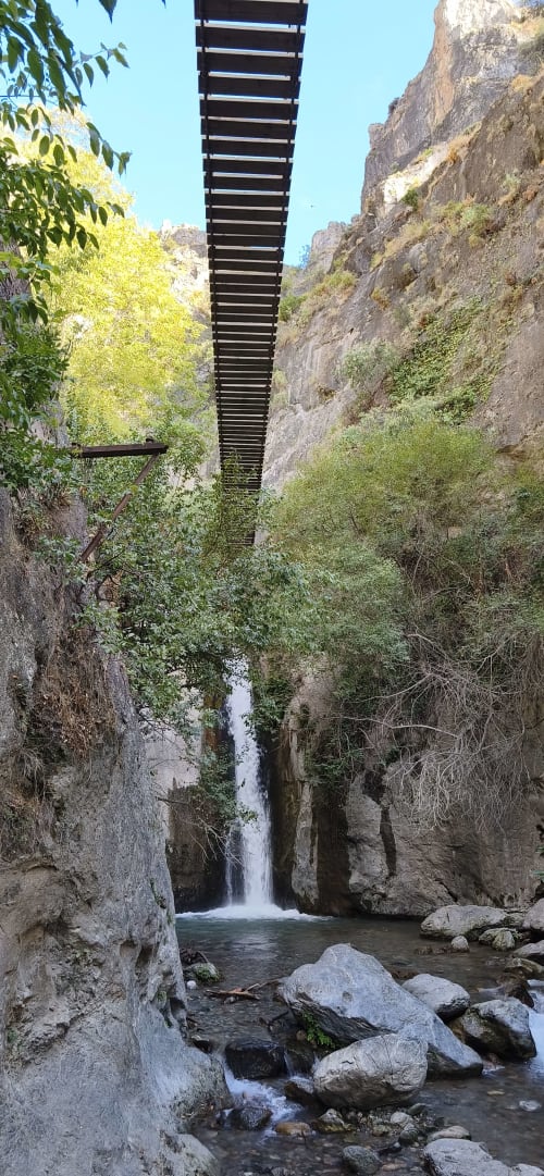Arroyo de montaña con cascada fluyendo entre rocas del cañón en Hospedería Puerta a los Cahorros, Monachil